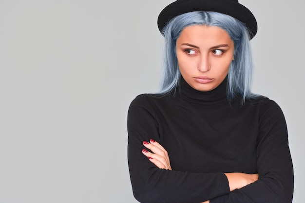 Photo horizontal portrait of beautiful young teenager woman with blue hair looking at one side with serious expression grumpy young female with dissatisfied expression copy space people lifestyle