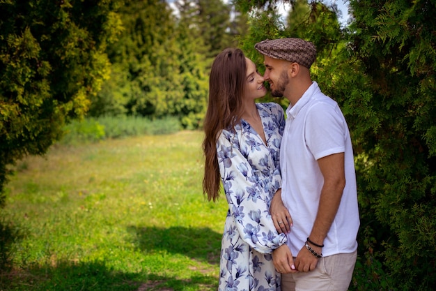 Horizontal portrait of charming couple in love hugs and holds hands at the green garden