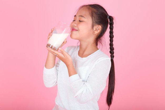 Horizontal portrait of a cute beautiful Asian little kid girl holding milk box isolated on background