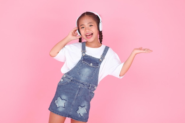 Horizontal portrait of a cute beautiful Asian little kid girl listening to music with headset isolated on background