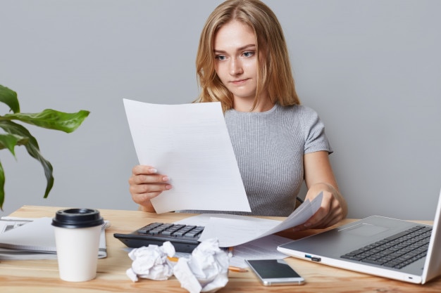 Horizontal portrait of successful businesswoman reads attentively business papers