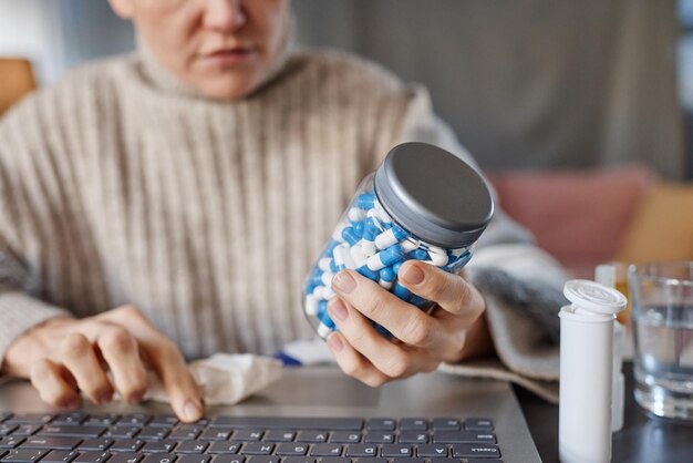 Horizontal selective focus shot of mature caucasian patient demonstrating pills to doctor during onl