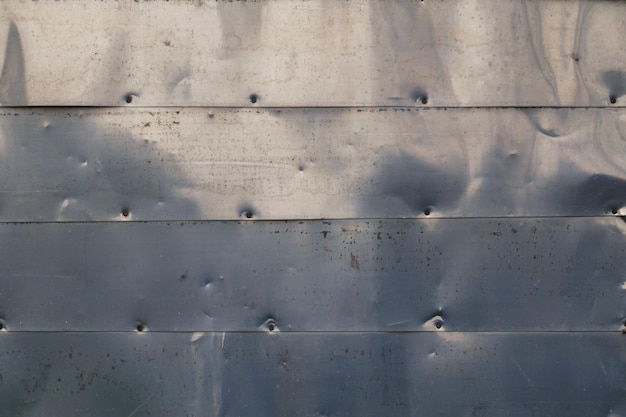 Horizontal shiny stainless steel sheets nailed to flat surface