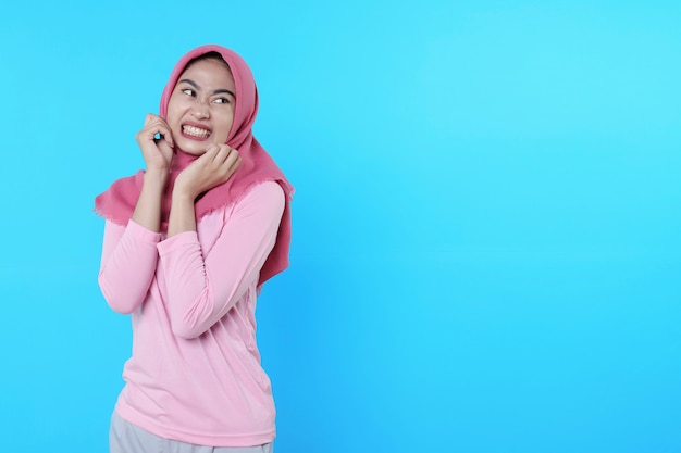 Horizontal shot of anxious good looking female in pink t shirt, nervously, frowning and looking aside