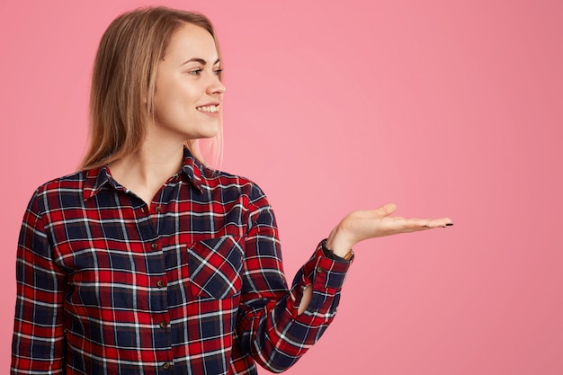 Horizontal shot of delighted young woman shop assistant raises pam