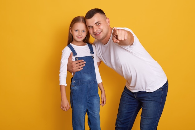 Horizontal shot of fashionable young father pointing finger at camera,