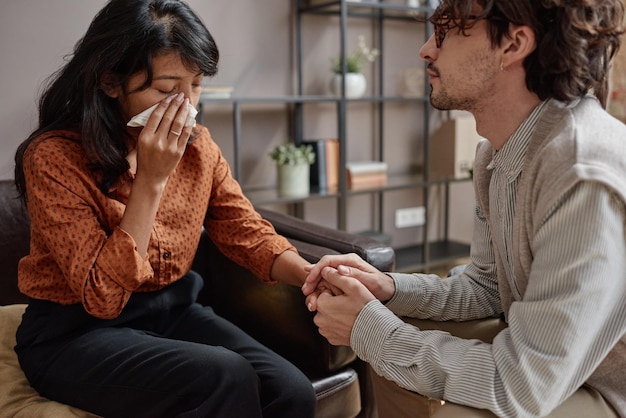 Horizontal shot of modern professional psychotherapist comforting depressed woman crying during sess