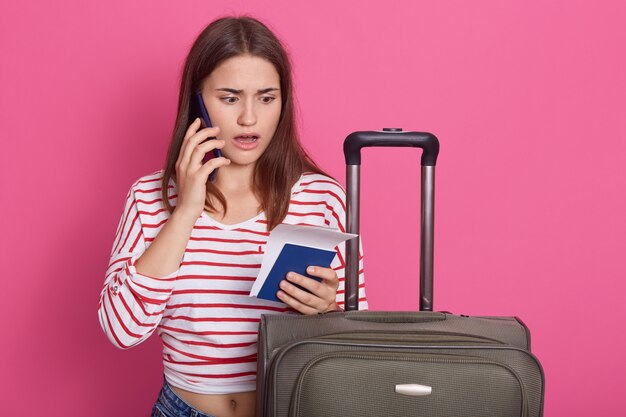 Horizontal shot of upset woman with baggage and documents