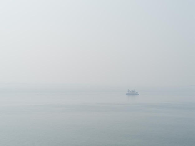 白い海の背景の背景に水平のまばらな淡い孤独な船