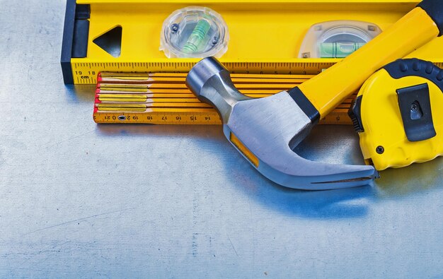 Horizontal view of construction level tape line claw hammer wooden meter on metallic background maintenance concept