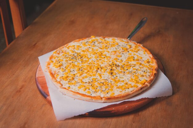 Horizontal view of a corn pizza on a wooden table