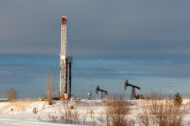Photo horizontal view of a derrick drilling and pump jack in severe winter.  extraction of oil. petroleum concept.
