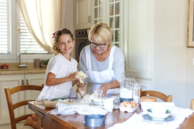 Horizontal view. A happy grandmother and niece is cooking. A smiling grandmother is cooking a cookies.