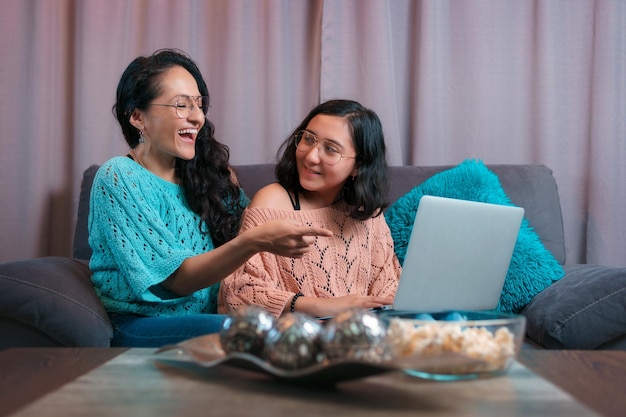 Horizontal view of a mother and her daughter using a laptop the mother laughs at something she saw on the computer and her daughter turns to see what her mother is doing