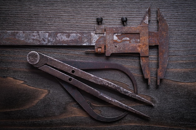 Horizontal view of obsolete trammel calipers on vintage wooden background