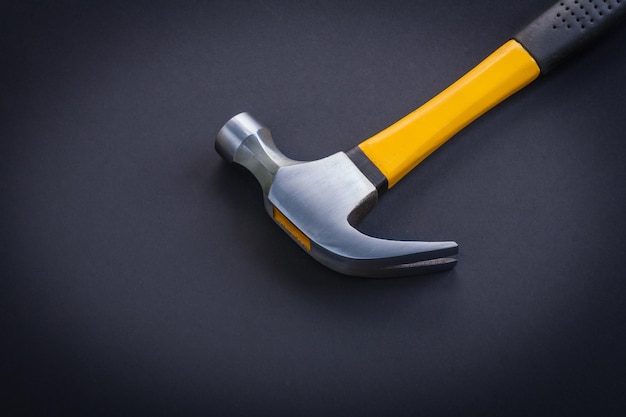 Horizontal view very close up view claw hammer with yellow and rubber handle on black background