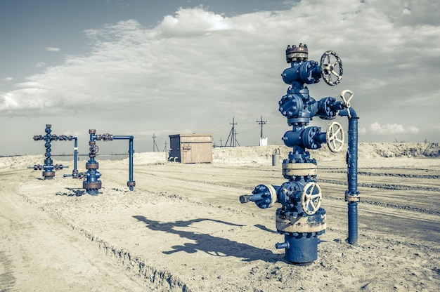 Horizontal view of a wellhead with valve armature. Oil and gas industry concept. Industrial site background. Toned.