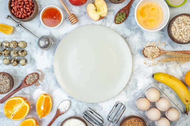 Vista orizzontale del piatto bianco e degli ingredienti per la selezione di cibi sani sulla superficie di marmo