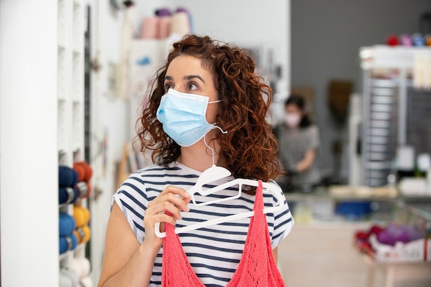 Horizontal view of woman wearing a face mask going shopping clothes