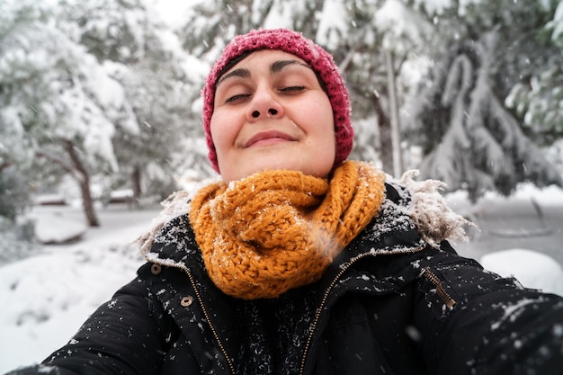 雪の下で屋外で新鮮な空気を呼吸している若い白人女性の水平方向のビュー。