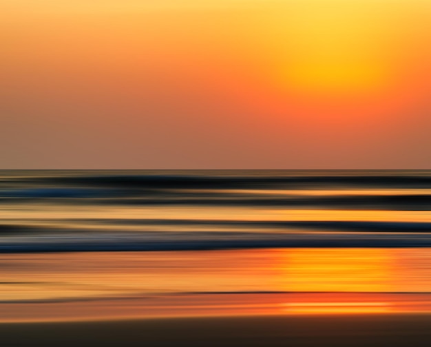 水平方向の鮮やかなオレンジ色の黄金色のインド洋の夕日の動きの抽象化の背景背景