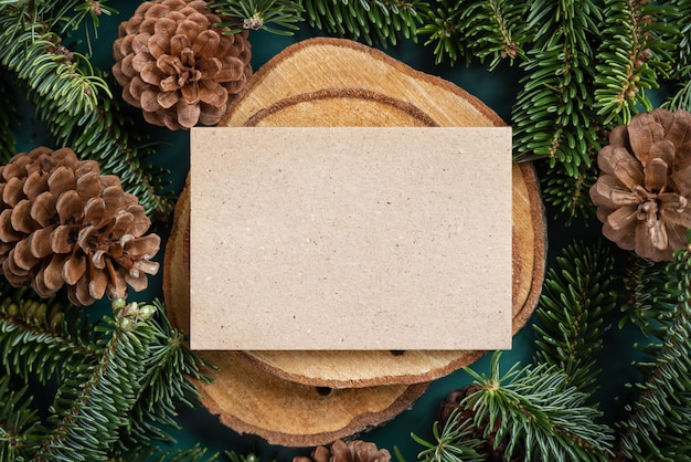 Horizontale blanco kerstkaart tussen dennentakken en dennenappels op groen bovenaanzicht