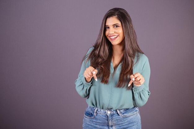 Horizontale foto Mooie Braziliaanse vrouw met vrijetijdskleding Jeans en groen shirt teken alleen hier wijzend naar het midden