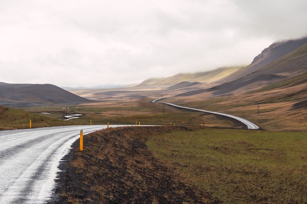 Foto horizontale opname van een landschap in ijsland met een lange asfaltweg