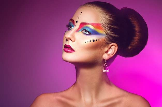 Horizotnal portrait of attractive woman with multicolor make up on purple