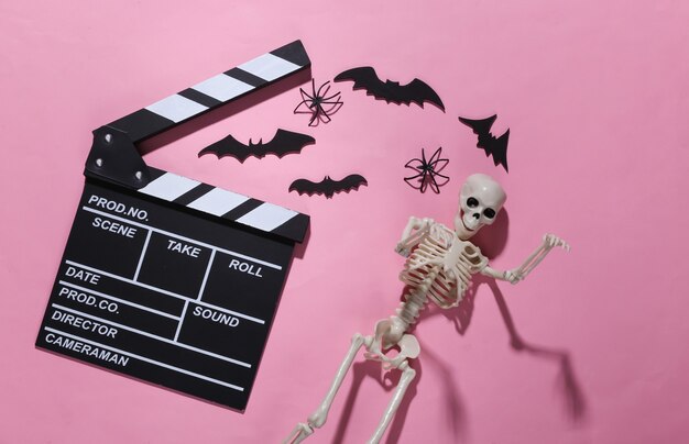 Film horror, tema di halloween. ciak di film, scheletro, ragni e pipistrelli decorativi volanti su rosa brillante