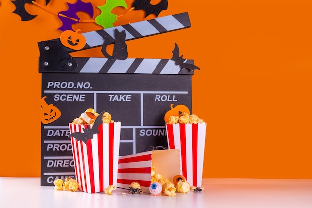 Horrorfilmserie nacht Halloween-bioscoopfeest met trickortreating snoep emmer popcorn film Filmklapper en Halloween-decoraties op hooggekleurde achtergrondkopieruimte