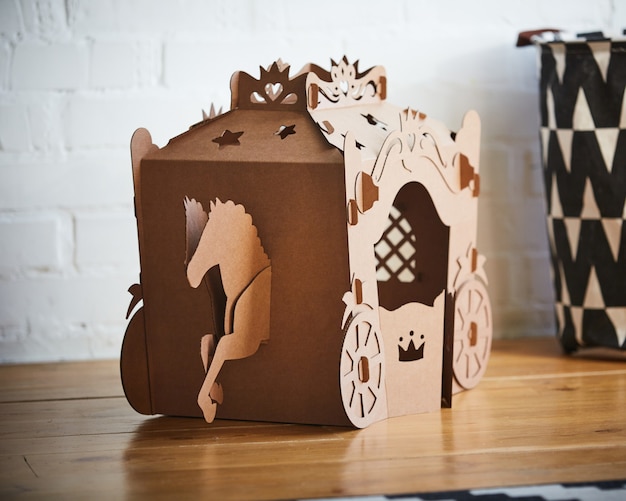 A horse and a carriage made of brown cardboard,where the horse is pulling the carriage