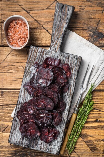 Horse game meat cured sausage with rosemary on a cutting board\
wooden background top view