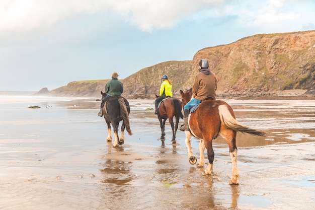 Foto passeggiata a cavallo sulla spiaggia in galles al tramonto