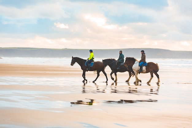 Horse riding on the beach at sunset in Wales