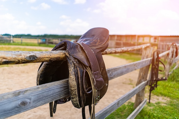 Horse saddle hanging on a fence close-up