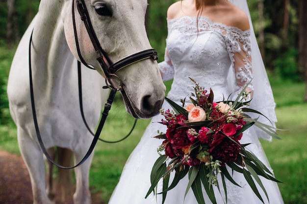 horse sniffing a bouquet of flowers in the hands of the bride