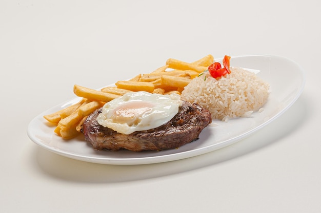 Horse steak meat and fried egg served with rice and fries