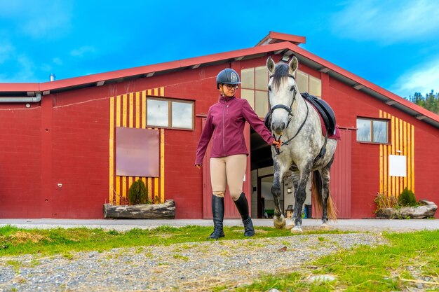 Foto un addestratore di cavalli e un cavallo bianco che camminano lungo un centro di riabilitazione