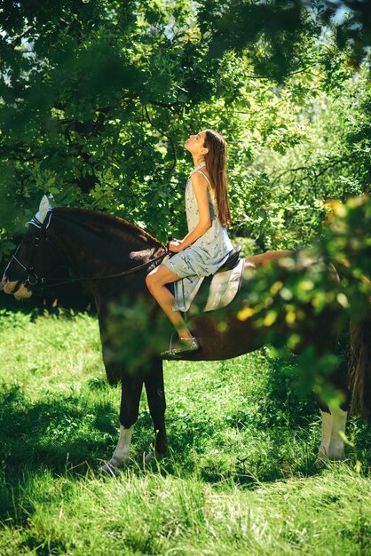 Horse training can be fun young woman riding horse on summer\
landscape pretty girl at horse ranch adorable horse owner with her\
pet making friends with horse taming and training