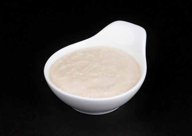 Horseradish sauce in white bowl isolated on black background