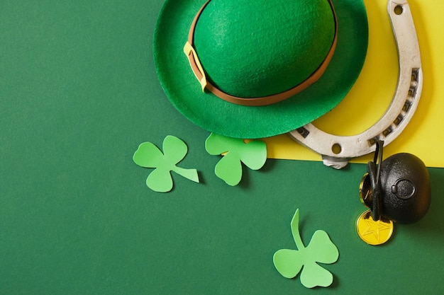 Horseshoe leprechaun hat coins cauldron and foamiran clover leaves on green background st patrick's day concept