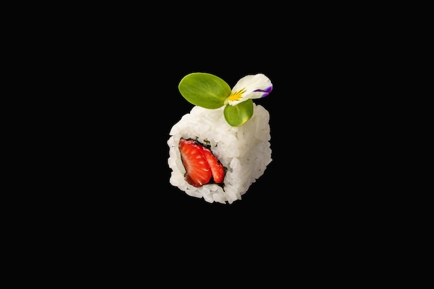 Hosomaki roll with strawberries unagi sauce microgreens rice isolated on black background