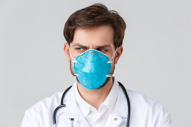 Hospital, healthcare workers, covid-19 treatment concept. Close-up of troubled and concerned doctor in medical respirator and scrubs, looking away with frowning face, feel nervous or upset, thinking