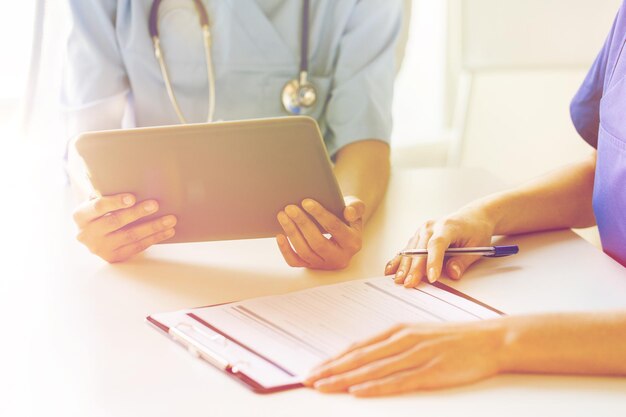 Foto ospedale, professione, persone e concetto di medicina - primo piano di medici con computer tablet pc e riunione negli appunti presso l'ufficio medico