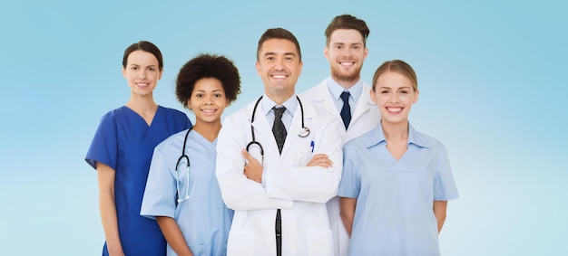 Photo hospital, profession, people and medicine concept - group of happy doctors over blue background