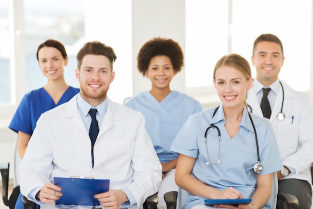 Hospital, profession, people and medicine concept - group of\
happy doctors on seminar in lecture hall at hospital