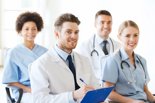 Hospital, profession, people and medicine concept - group of\
happy doctors with clipboard on seminar in lecture hall at\
hospital