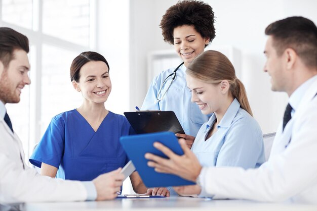 Foto concetto di ospedale, professione, persone e medicina - gruppo di medici felici con computer tablet pc che si incontrano presso l'ufficio medico