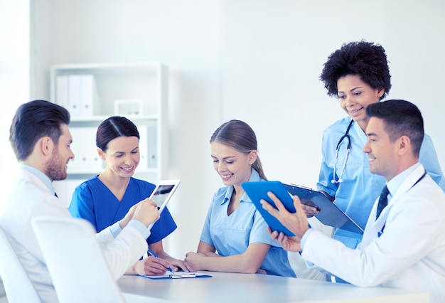 병원, 직업, 사람 및 의학 개념 - 태블릿 PC 컴퓨터를 가진 행복한 의사 그룹이 의료 사무실에서 만납니다.